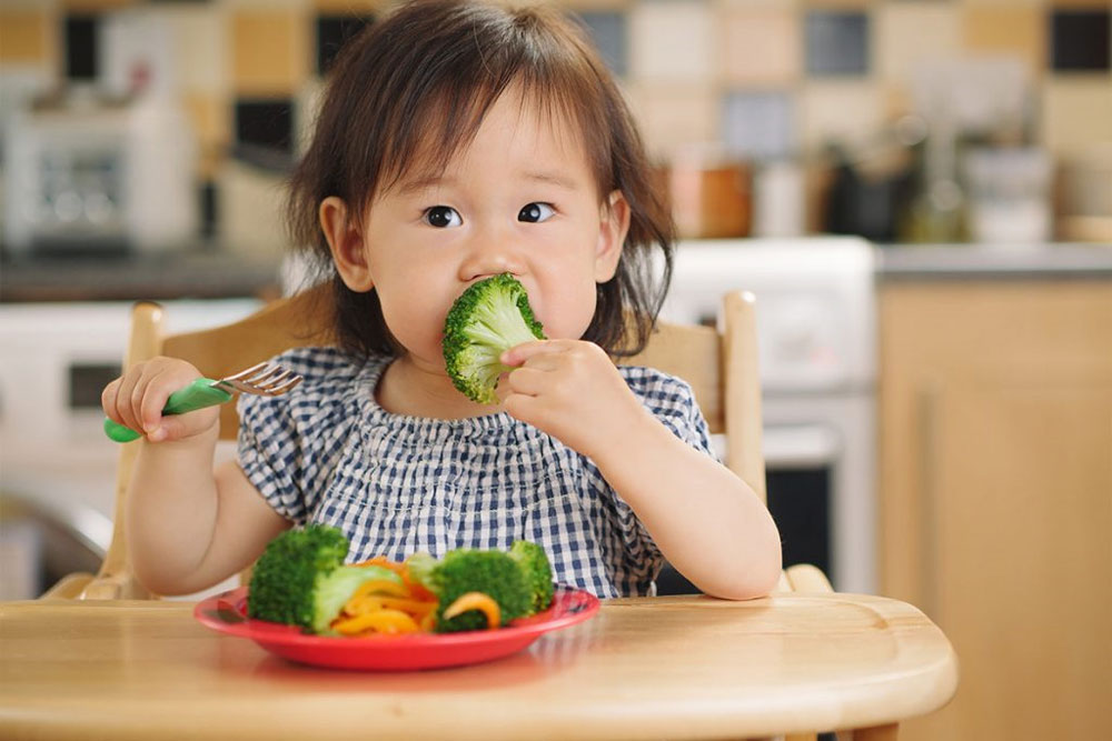 کودکی در حال بروکلی خوردن